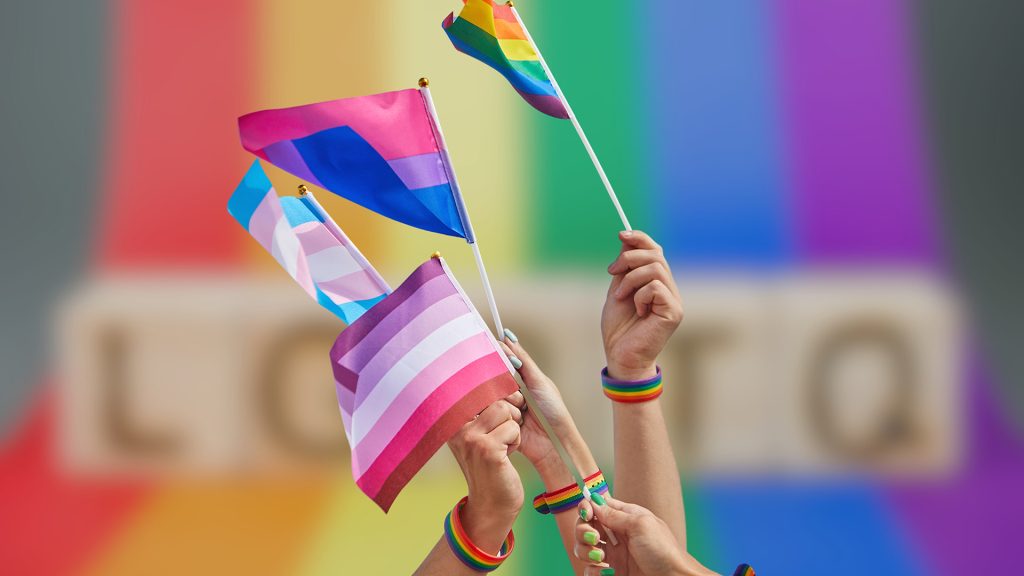 Mains tenant des drapeaux multicolores.